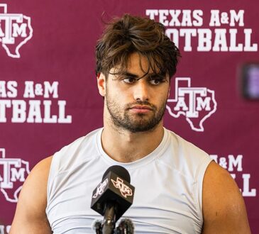 Texas A&M's Noah Mikhail sits in front of a Texas A&M Football backdrop while speaking to reporters.