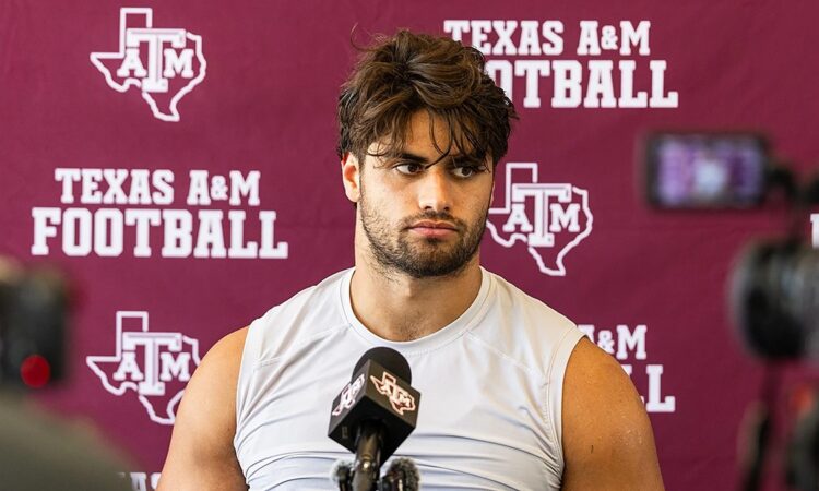 Texas A&M's Noah Mikhail sits in front of a Texas A&M Football backdrop while speaking to reporters.
