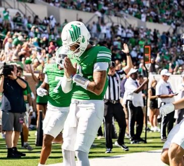 A North Texas player bows his head with his hands together in the end zone after a touchdown against UNLV.