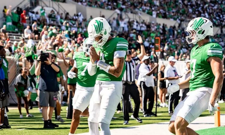 A North Texas player bows his head with his hands together in the end zone after a touchdown against UNLV.