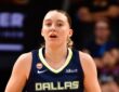 Dallas Wings guard Paige Bueckers dribbles up the court in a navy Dallas jersey during a road game.