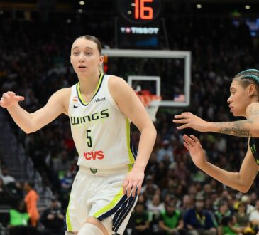Dallas Wings guard Paige Bueckers flicks a pass as a Seattle Storm defender closes in.