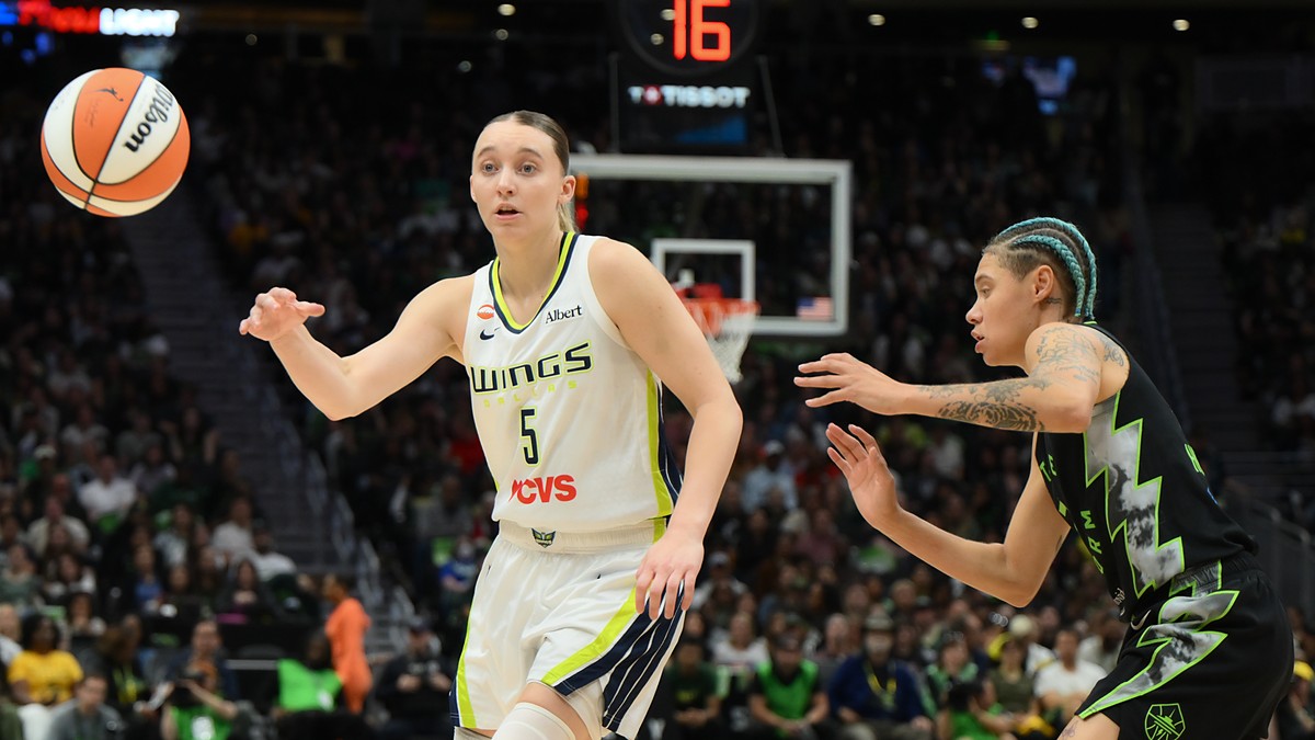 Dallas Wings guard Paige Bueckers flicks a pass as a Seattle Storm defender closes in.