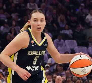 Dallas Wings guard Paige Bueckers dribbles to her left as two Golden State Valkyries defenders close in.