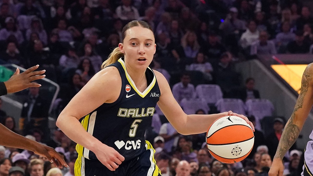 Dallas Wings guard Paige Bueckers dribbles to her left as two Golden State Valkyries defenders close in.