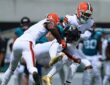 Jaguars receiver Parker Washington is wrapped up by Browns defenders Tyson Campbell and Grant Delpit after a catch.