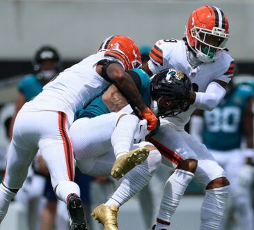 Jaguars receiver Parker Washington is wrapped up by Browns defenders Tyson Campbell and Grant Delpit after a catch.