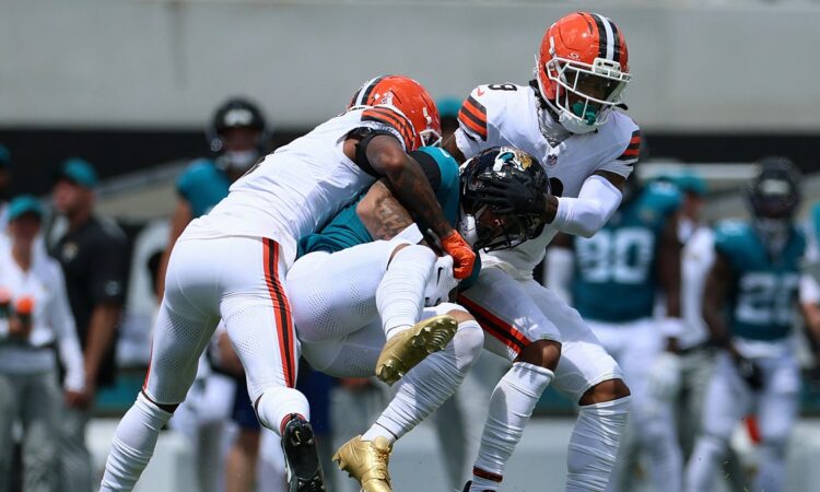 Jaguars receiver Parker Washington is wrapped up by Browns defenders Tyson Campbell and Grant Delpit after a catch.