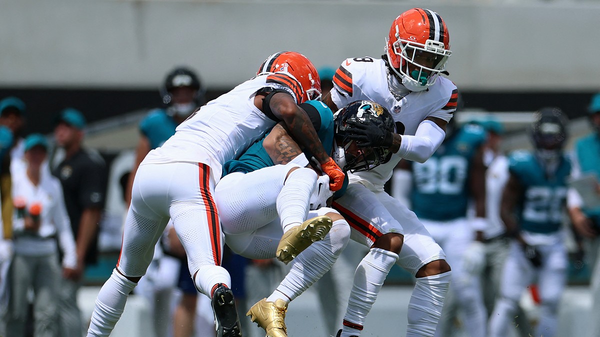 Jaguars receiver Parker Washington is wrapped up by Browns defenders Tyson Campbell and Grant Delpit after a catch.