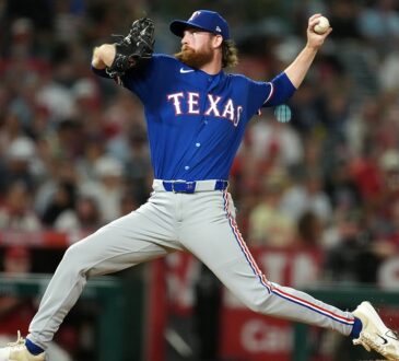 Texas Rangers pitcher Peyton Gray strides toward the plate mid-delivery in a road gray uniform.