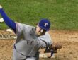 Texas Rangers pitcher Peyton Gray, seen from above, extends his arm back to throw from the mound in his road uniform.