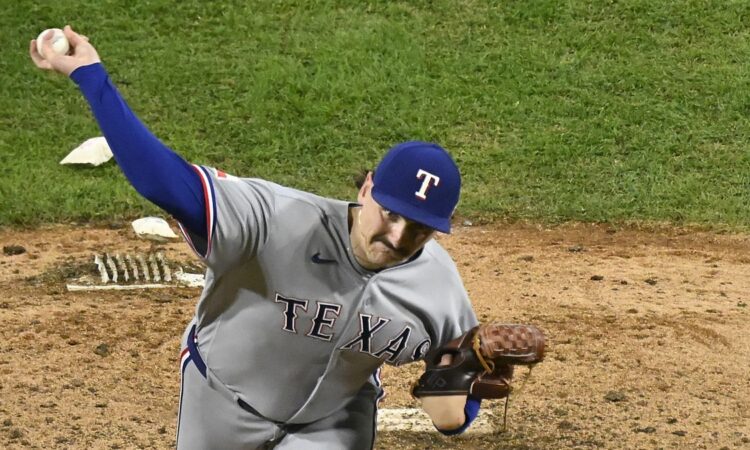 Texas Rangers pitcher Peyton Gray, seen from above, extends his arm back to throw from the mound in his road uniform.