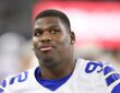 Dallas Cowboys defensive tackle Quinnen Williams looks upward while standing without his helmet.