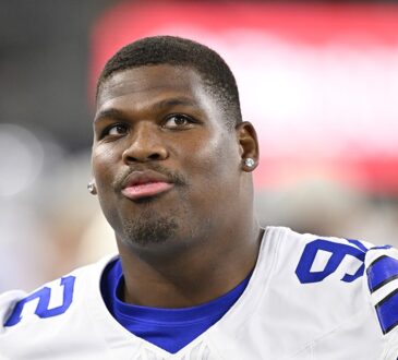 Dallas Cowboys defensive tackle Quinnen Williams looks upward while standing without his helmet.