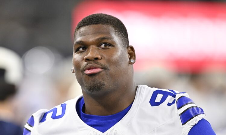 Dallas Cowboys defensive tackle Quinnen Williams looks upward while standing without his helmet.