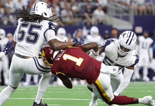 Washington Commanders running back Rachaad White is spun backward as two Dallas Cowboys linebackers bring him down.