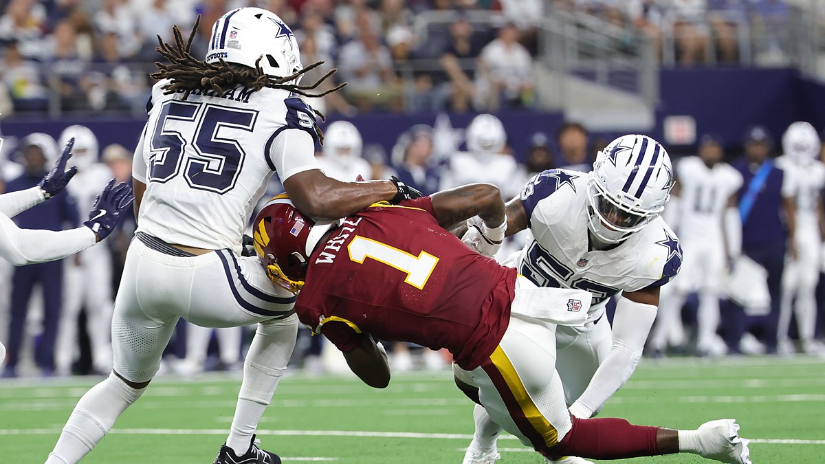 Washington Commanders running back Rachaad White is spun backward as two Dallas Cowboys linebackers bring him down.