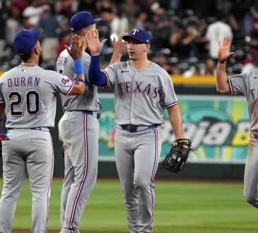 Texas Rangers players exchange high fives on the infield after a win over the Arizona Diamondbacks.