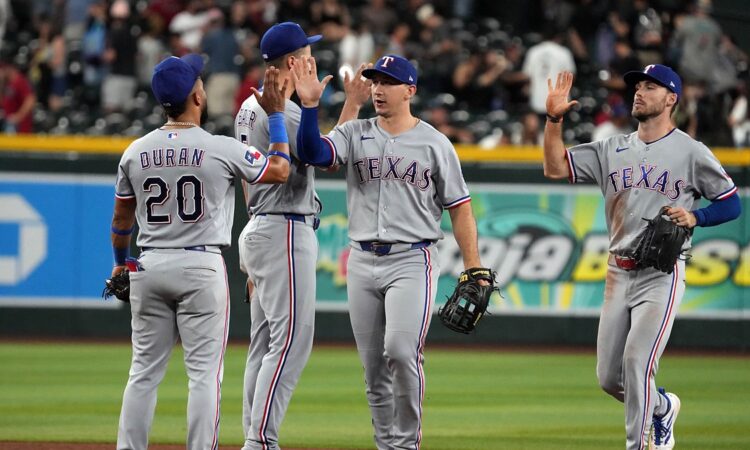 Texas Rangers players exchange high fives on the infield after a win over the Arizona Diamondbacks.