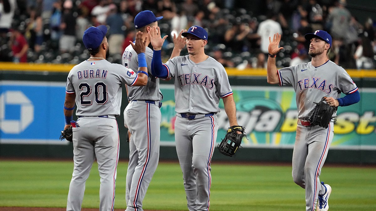Texas Rangers players exchange high fives on the infield after a win over the Arizona Diamondbacks.