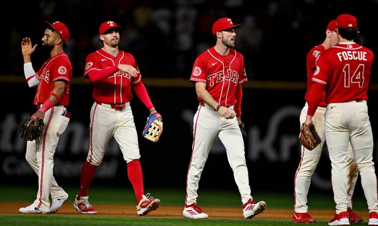 Texas Rangers players walk off the field together after a win, one raising his hand for a high-five.
