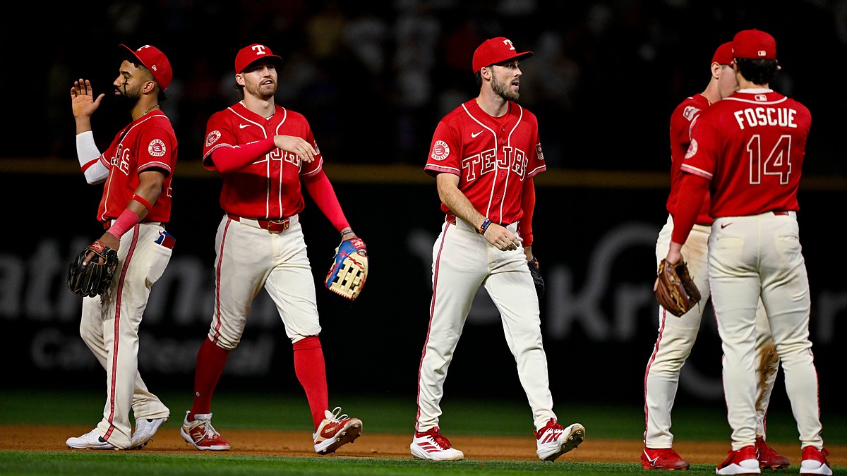 Texas Rangers players walk off the field together after a win, one raising his hand for a high-five.