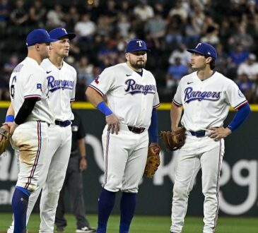 Texas Rangers infielders Josh Jung, Corey Seager, Jacob Burger, and Justin Foscue gather on the infield during a pause.