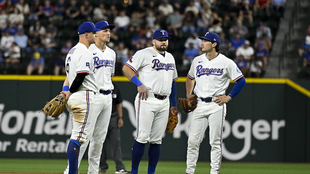 Texas Rangers infielders Josh Jung, Corey Seager, Jacob Burger, and Justin Foscue gather on the infield during a pause.