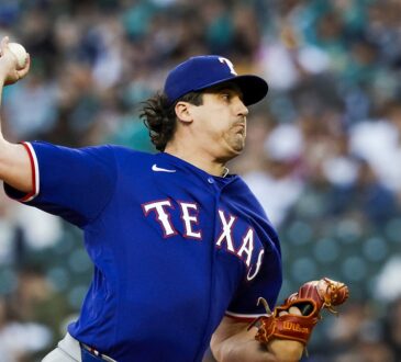 A Texas Rangers pitcher raises the ball in his delivery during a game against the Seattle Mariners.