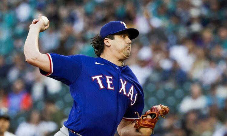 A Texas Rangers pitcher raises the ball in his delivery during a game against the Seattle Mariners.