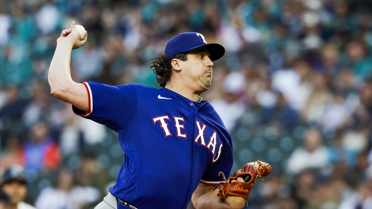 A Texas Rangers pitcher raises the ball in his delivery during a game against the Seattle Mariners.