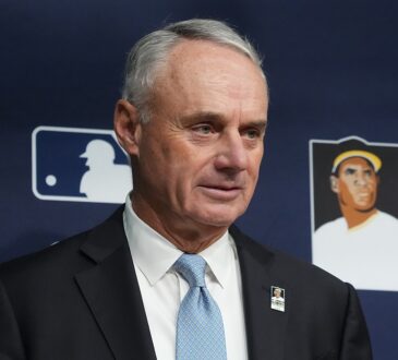 Major League Baseball commissioner Rob Manfred stands in front of an MLB backdrop before a World Series game.