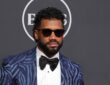 Russell Wilson poses in a patterned blue tuxedo jacket and sunglasses on the ESPY Awards red carpet.