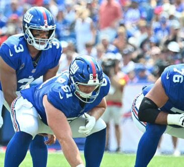 New York Giants quarterback Russell Wilson, No. 3, stands behind center John Michael Schmitz Jr. at the line of scrimmage.
