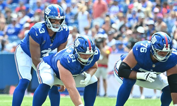 New York Giants quarterback Russell Wilson, No. 3, stands behind center John Michael Schmitz Jr. at the line of scrimmage.