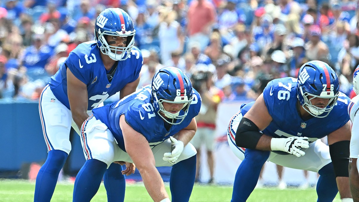 New York Giants quarterback Russell Wilson, No. 3, stands behind center John Michael Schmitz Jr. at the line of scrimmage.