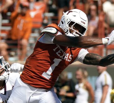 Texas Longhorns wide receiver Ryan Wingo, No. 1, stretches one hand toward the ball as a defender holds him.