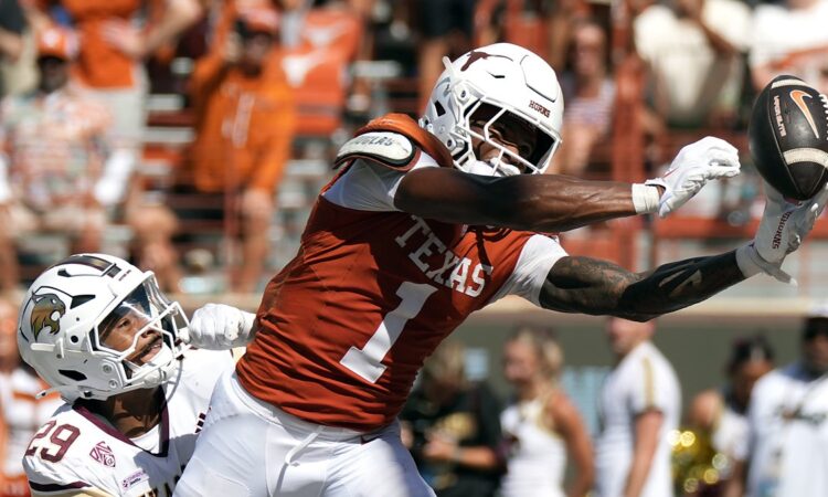Texas Longhorns wide receiver Ryan Wingo, No. 1, stretches one hand toward the ball as a defender holds him.