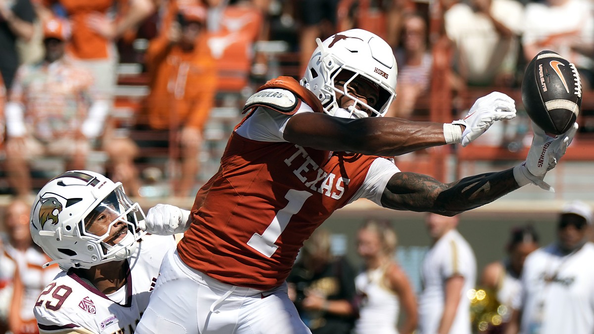 Texas Longhorns wide receiver Ryan Wingo, No. 1, stretches one hand toward the ball as a defender holds him.