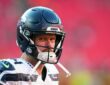 Seattle Seahawks quarterback Sam Darnold looks toward the field in his helmet before a game against the Chiefs.