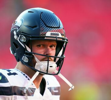Seattle Seahawks quarterback Sam Darnold looks toward the field in his helmet before a game against the Chiefs.