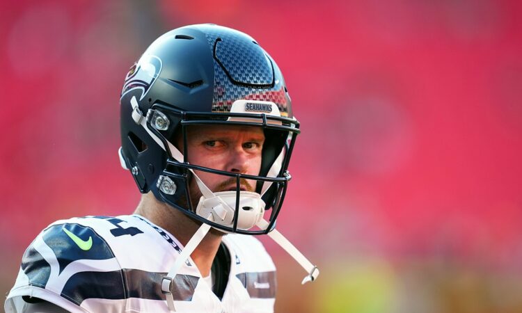 Seattle Seahawks quarterback Sam Darnold looks toward the field in his helmet before a game against the Chiefs.