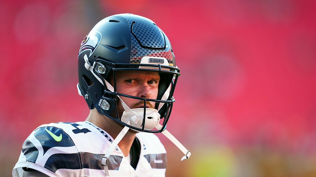 Seattle Seahawks quarterback Sam Darnold looks toward the field in his helmet before a game against the Chiefs.