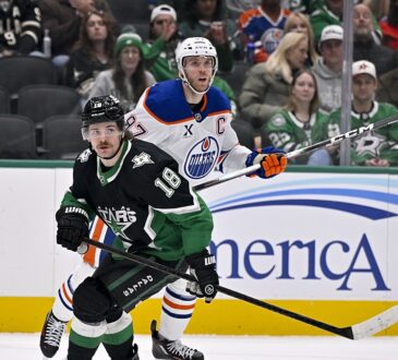 Stars center Sam Steel and Oilers center Connor McDavid skate side by side as both look up for the puck.