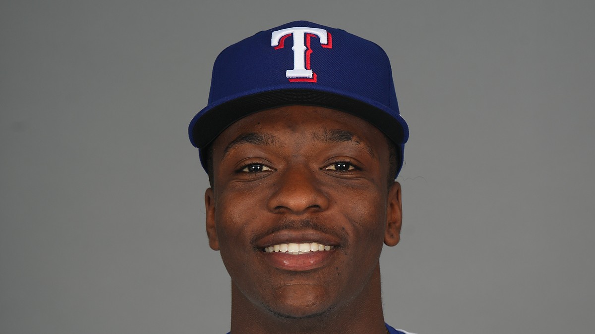 Texas Rangers infield prospect Sebastian Walcott poses in a cap and jersey during media day.