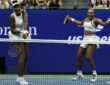 Venus Williams and Serena Williams shout and react at the net during a doubles point.