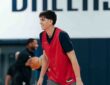 Dallas Mavericks guard Sergio de Larrea smiles in a red practice pinny on the team's practice court.