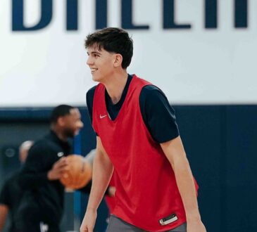 Dallas Mavericks guard Sergio de Larrea smiles in a red practice pinny on the team's practice court.