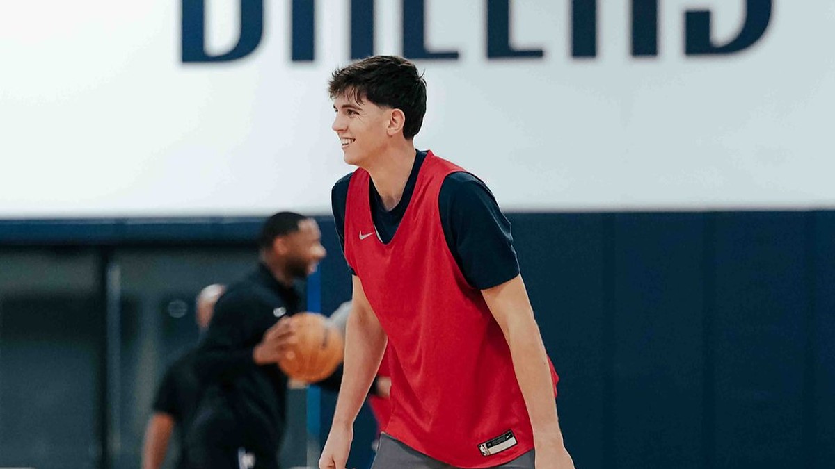 Dallas Mavericks guard Sergio de Larrea smiles in a red practice pinny on the team's practice court.