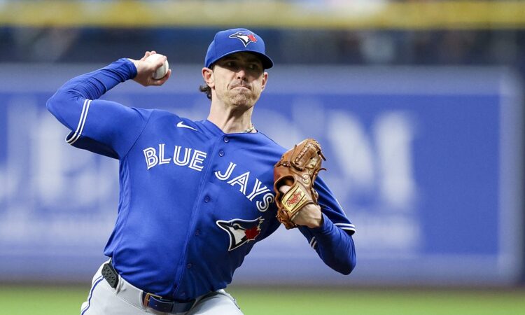 Toronto Blue Jays starting pitcher Shane Bieber rears back to throw a pitch from the mound in his road uniform.